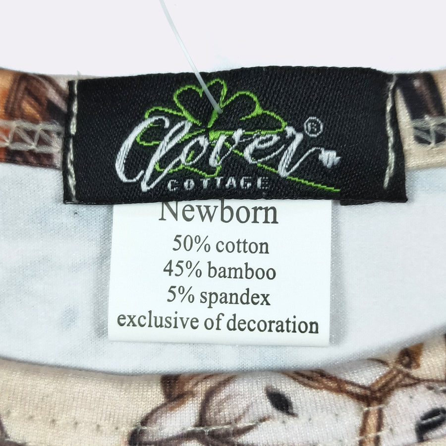 Close-up of a garment's interior neck label showing the brand Clover Cottage and a white care tag with fabric composition details.