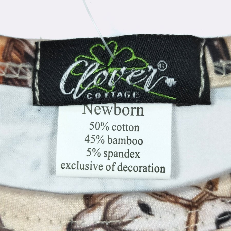 Close-up of a garment's interior neck label showing the brand Clover Cottage and a white care tag with fabric composition details.