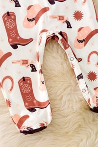 Patterned romper with cowboy boots, hats, and guns on a beige background