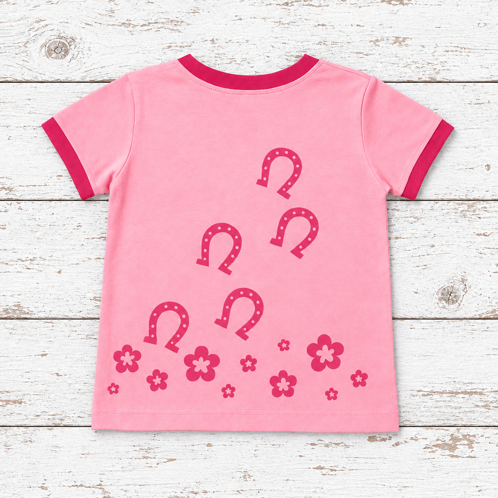 Pink horse t-shirt with horseshoe designs on a wooden surface
