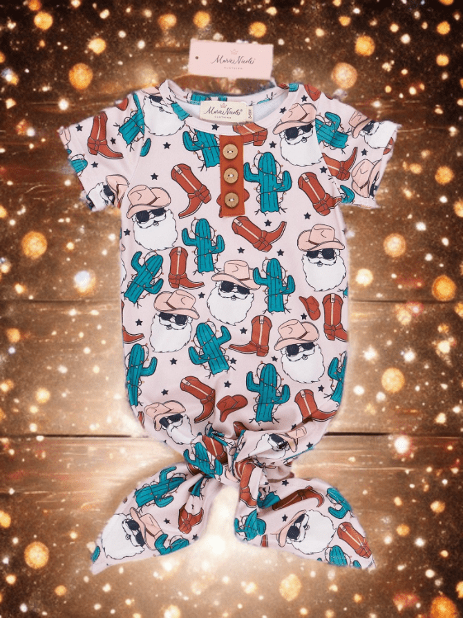 Christmas baby romper with cowboy and cactus pattern on a wooden surface