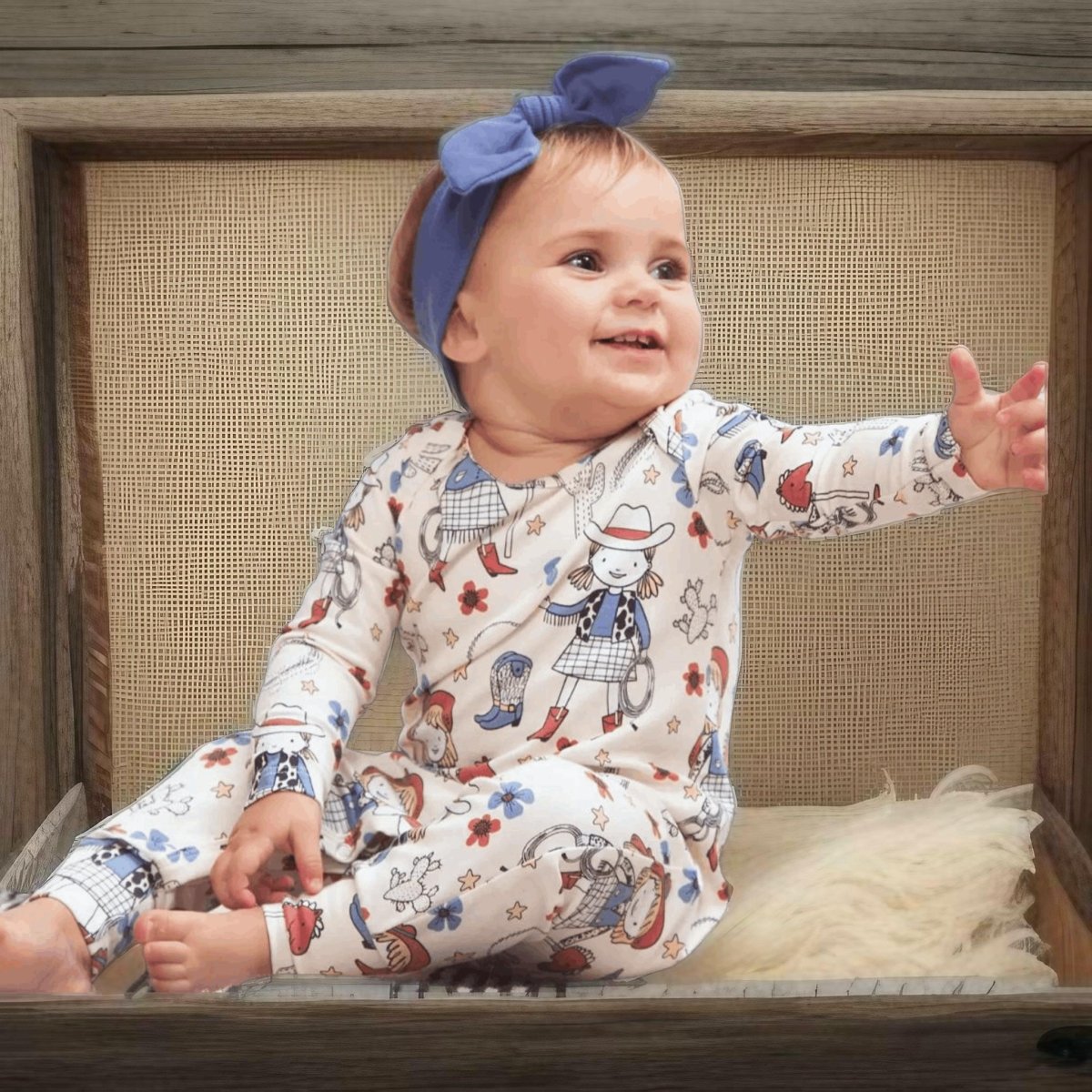 Baby girl in Annie Oakley western romper sitting on bench