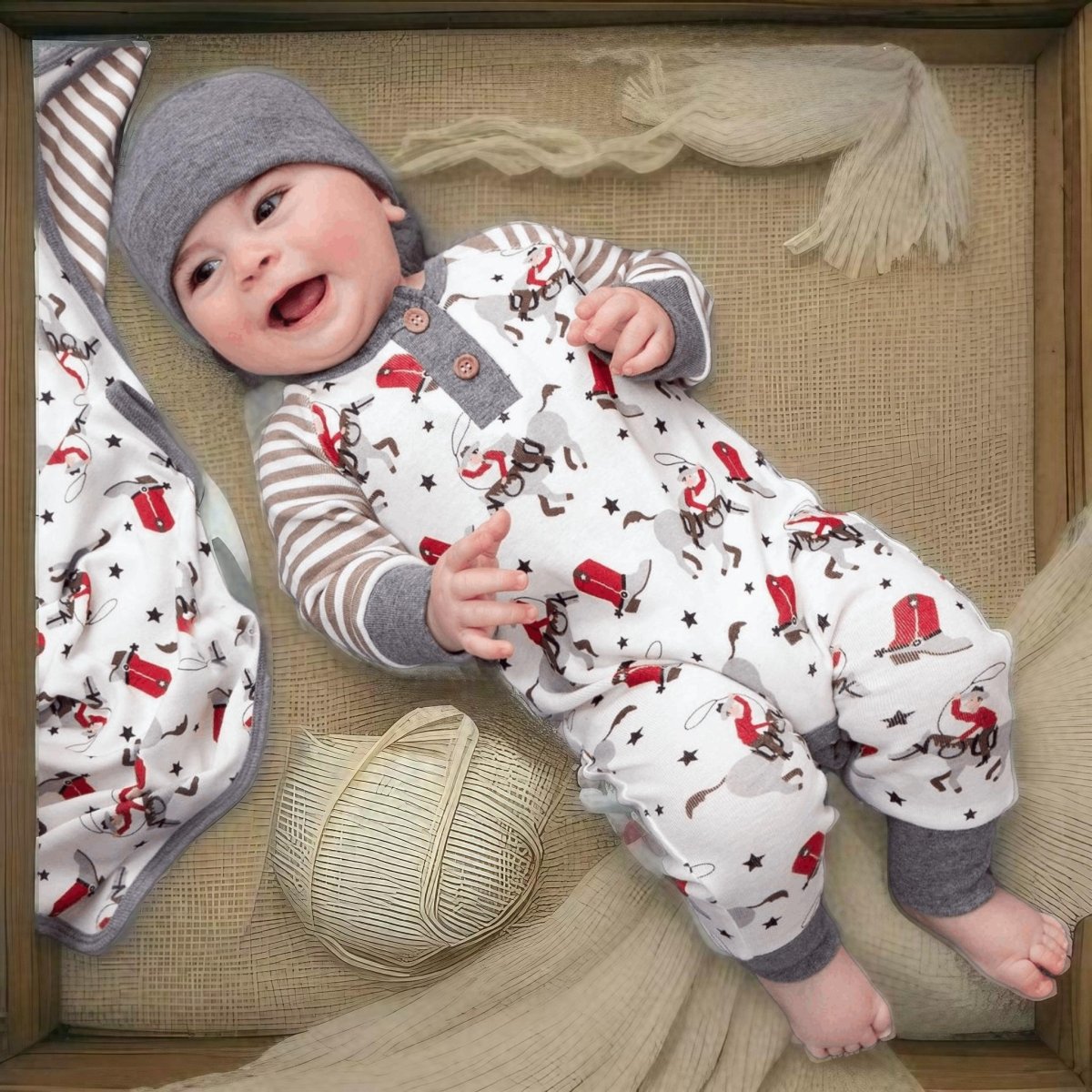 Baby laying in bamboo cowboy romper with hat and boots print