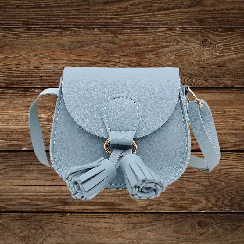 Blue mini crossbody purse with tassel detail on wood background.