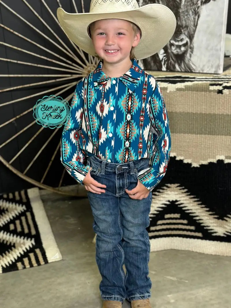 Full body view of boy in teal Aztec Western shirt with jeans and cowboy boots.