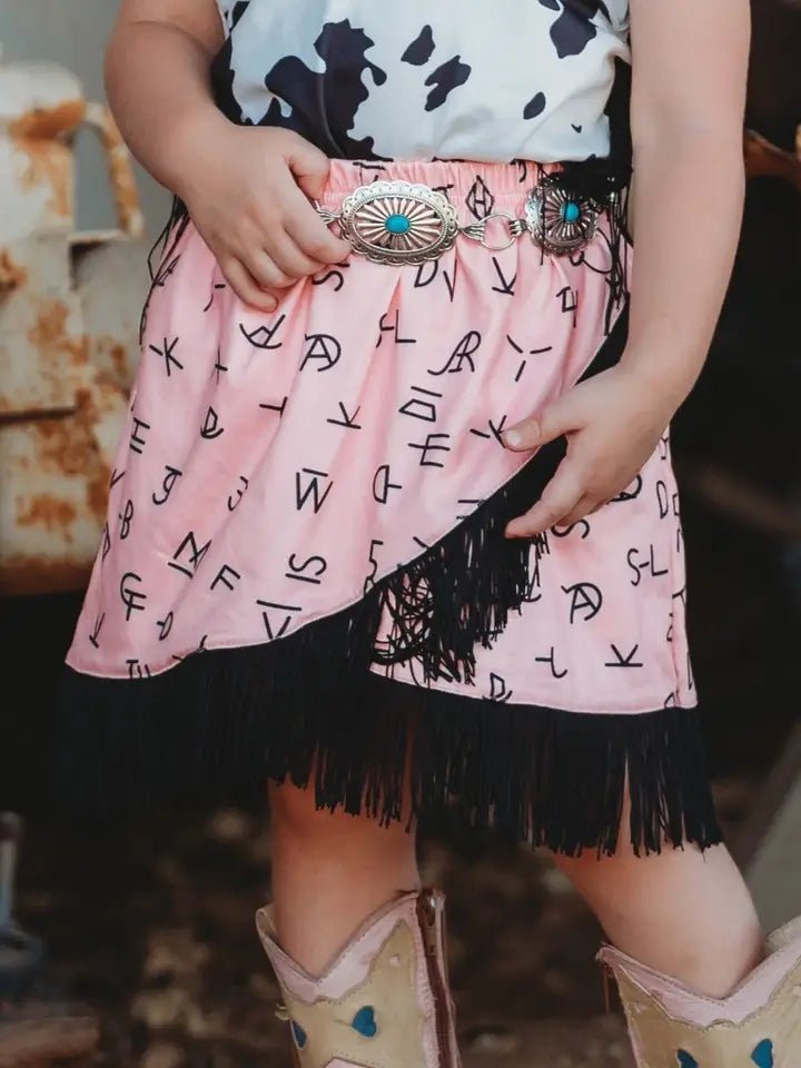 Close-up of branding iron print and fringe trim on cowgirl skirt