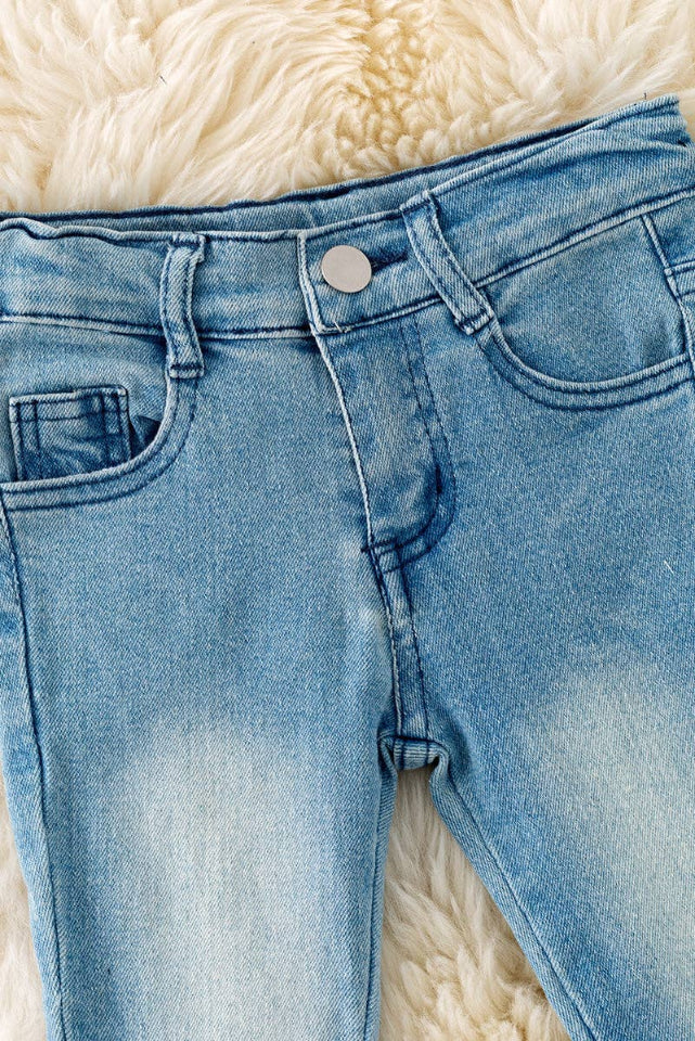 Close-up of waistband and pockets on girls' light blue western bell pants.