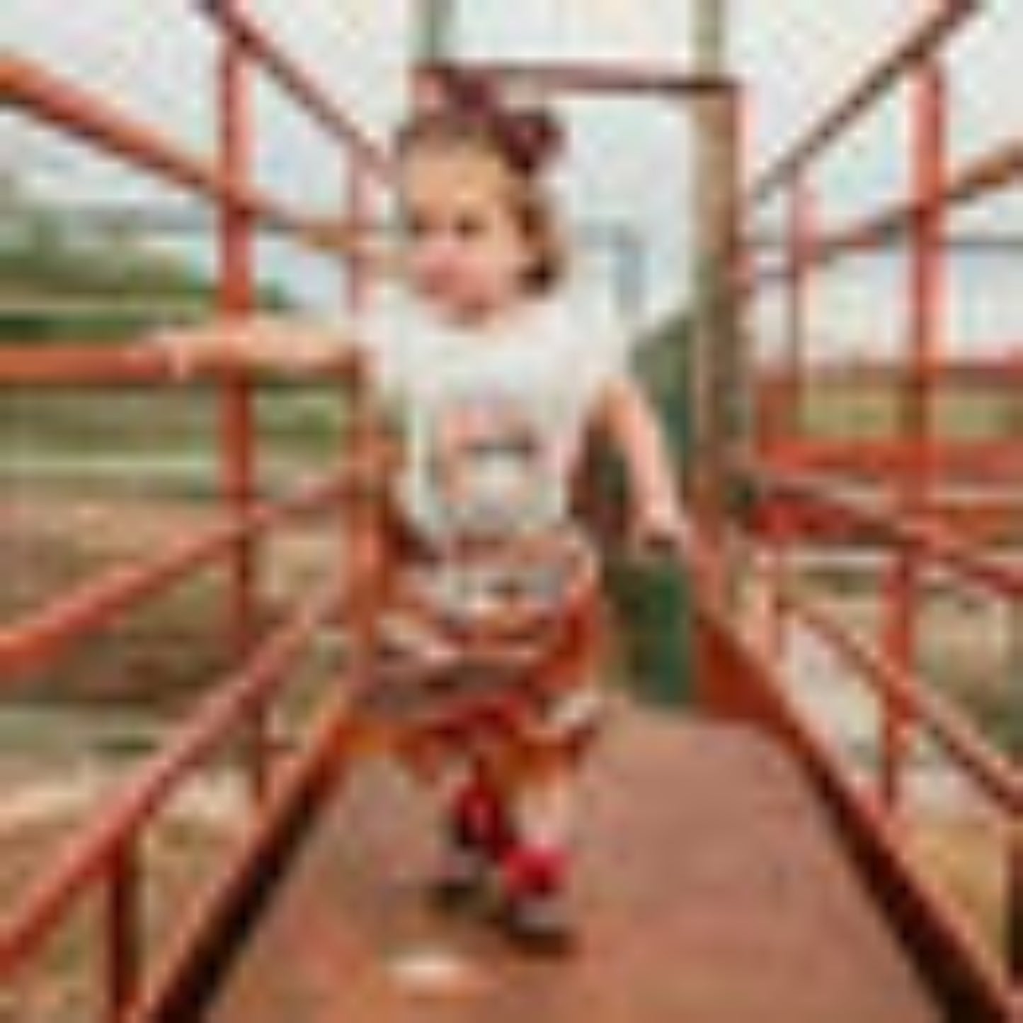 Girl in Proud Cowgirl tee walking by red fence