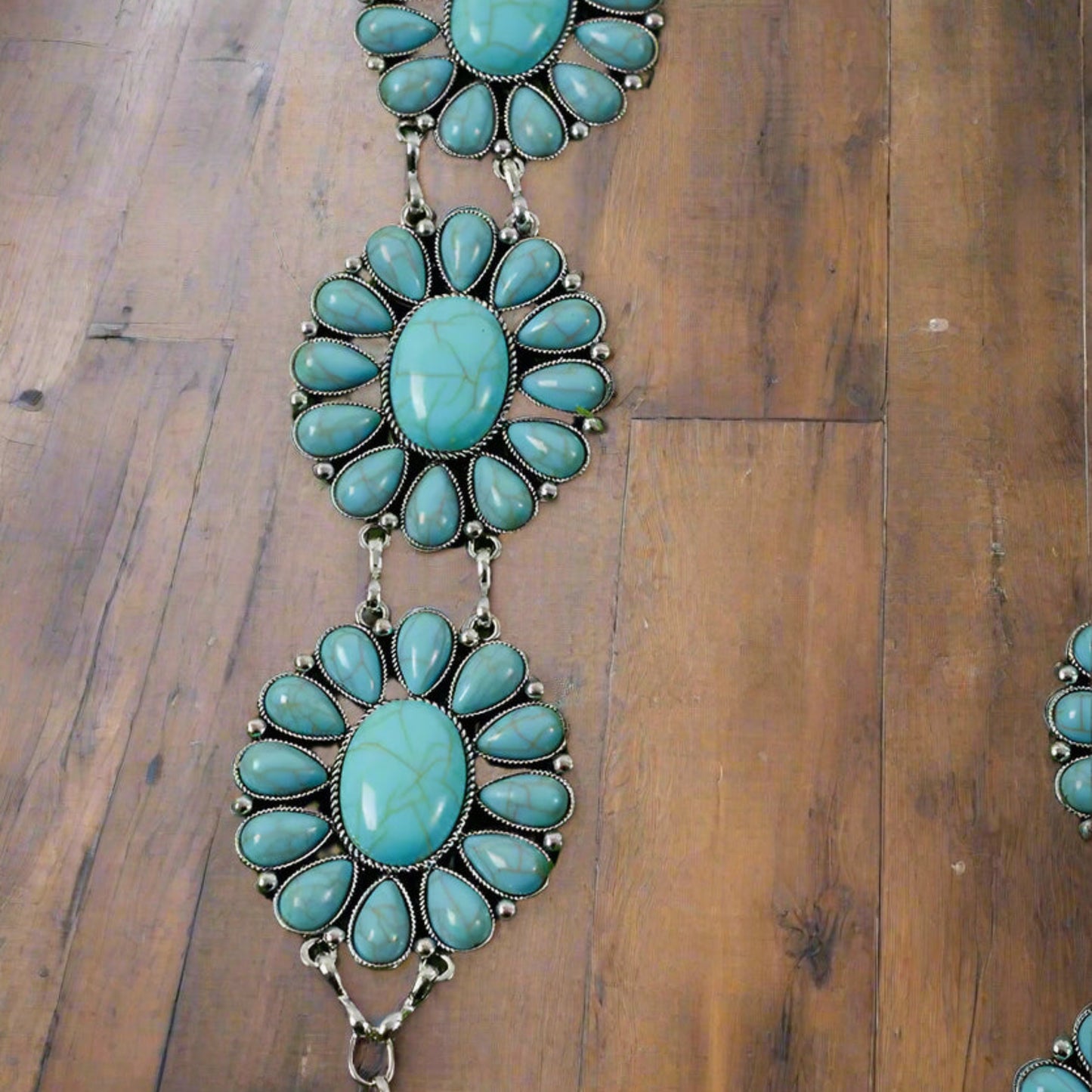 Detailed view of girls’ Western aqua concho belt with turquoise flower patterns on wood.