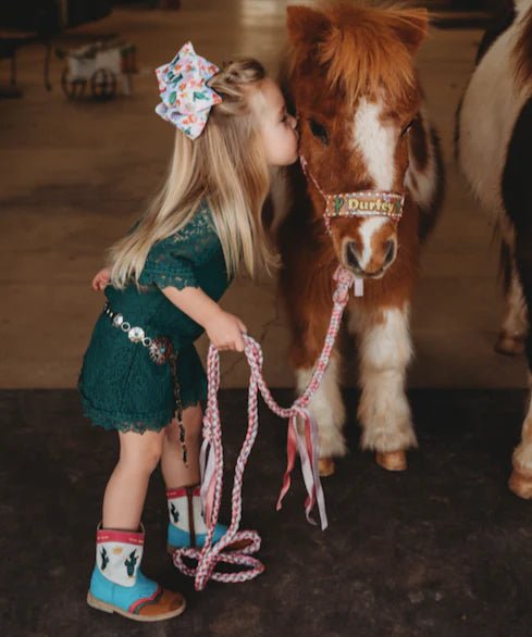 Girl kissing pony wearing cactus boots