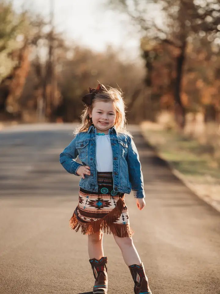 Young girl in Aztec fringe skirt posing outdoors