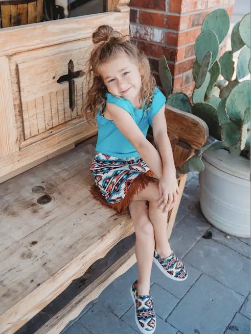 Young girl sitting on porch wearing Aztec kids sneakers