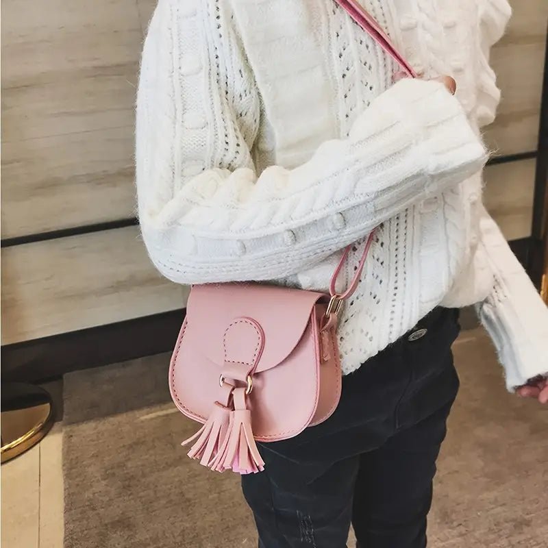 Girl wearing pink mini crossbody purse with tassel for cowgirl outfit.