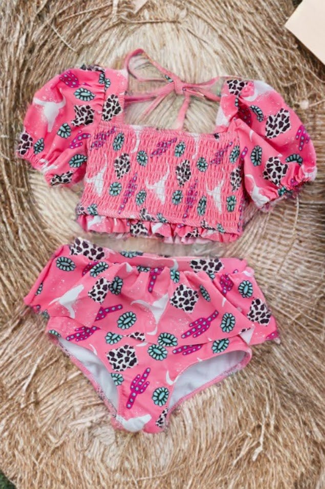 Girls’ pink cactus smocked swim set flatlay on straw