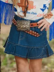 Girl wearing ruffled denim skirt, western belt, and fringe sleeve shirt