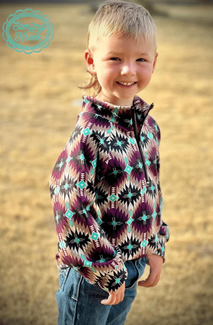 Boy in Mini Badlands Pullover featuring dark purple and turquoise vibrant southwestern Aztec pattern, perfect for chilly days on the ranch.