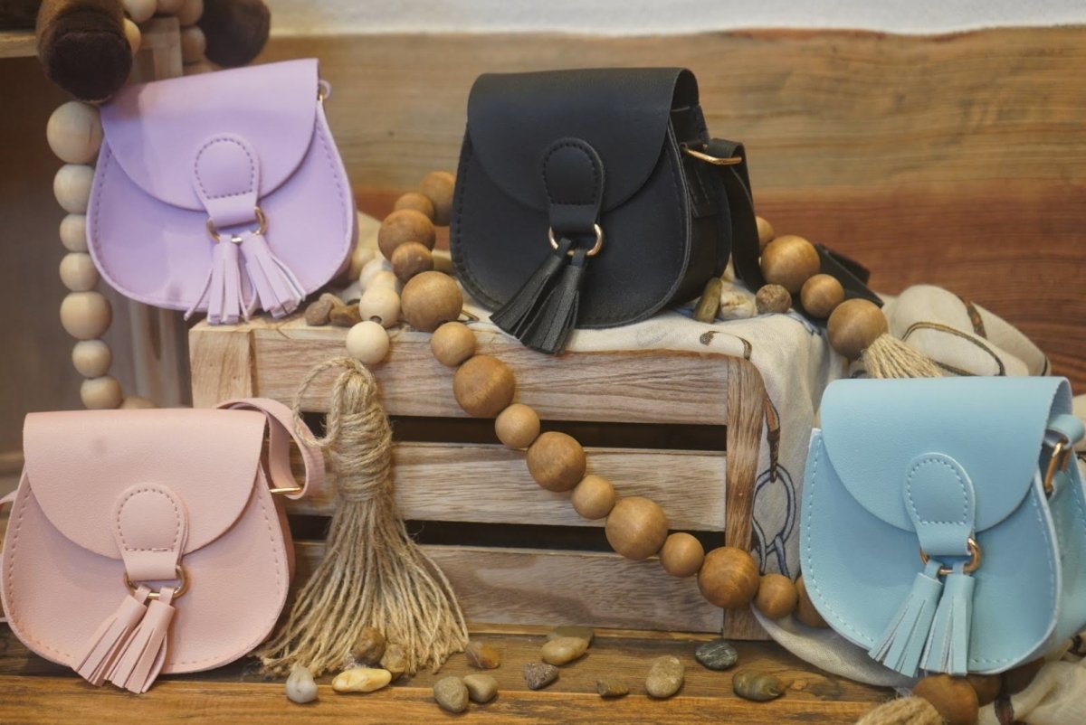 Multiple mini crossbody purses for girls in pastel colors displayed on rustic crates.