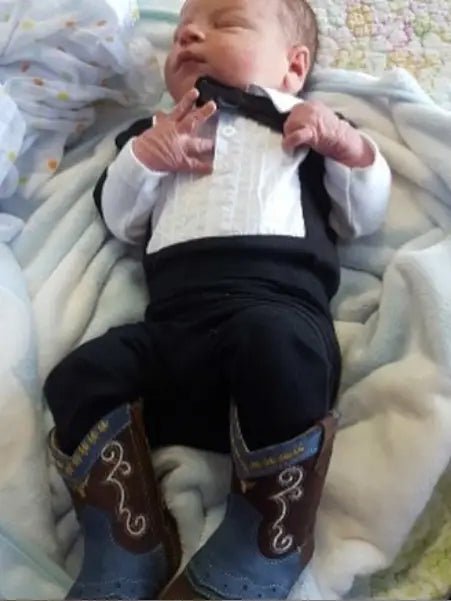 Newborn in Nash boots lying on white blanket