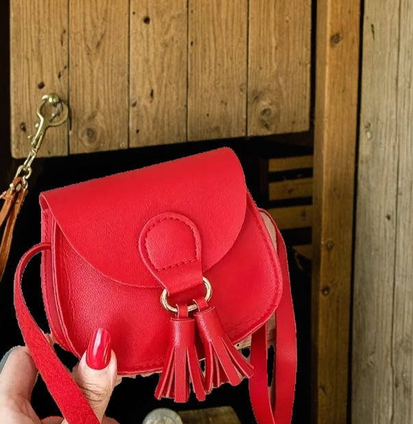 Red mini crossbody purse with tassel held in hand, Western-inspired.