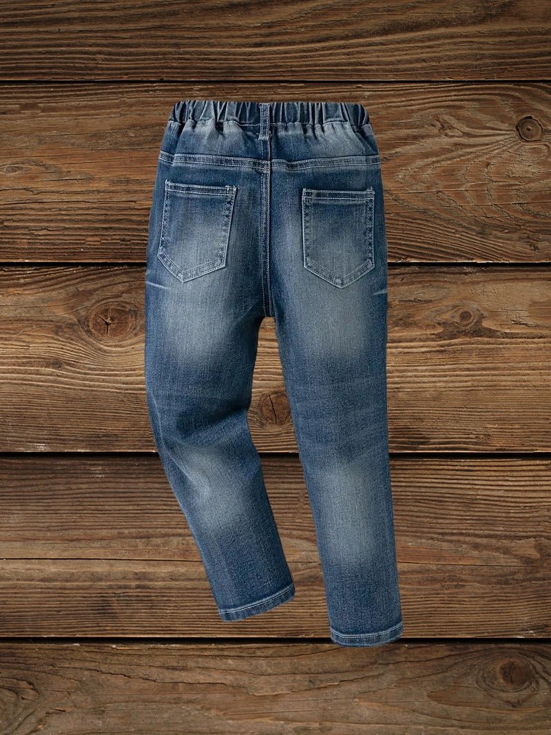 Boys' denim ripped jeans back view showing pockets on wooden background.
