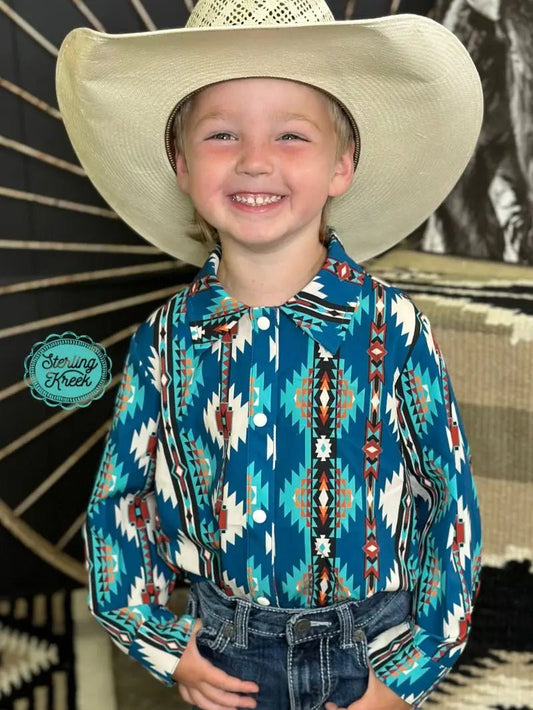 Smiling young boy wearing teal Aztec print long-sleeve Western shirt and cowboy hat.
