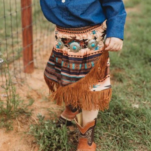 Child in western Aztec skirt and blue sweater in field