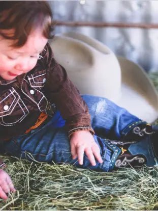 Baby boy in plaid wearing Nash boots on grass