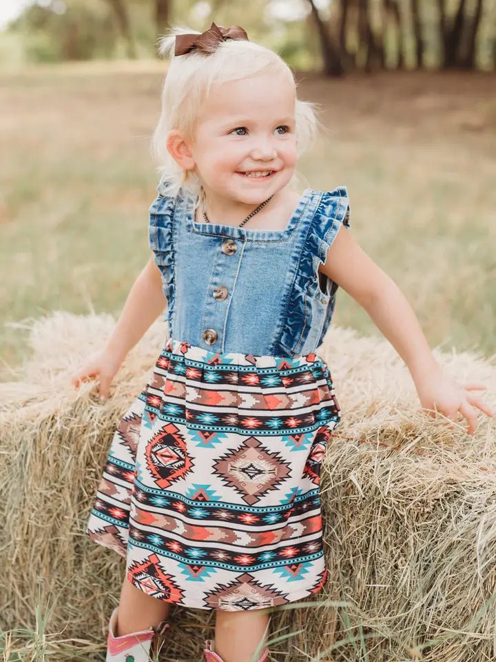 Toddler in denim and Aztec western dress smiling outdoors