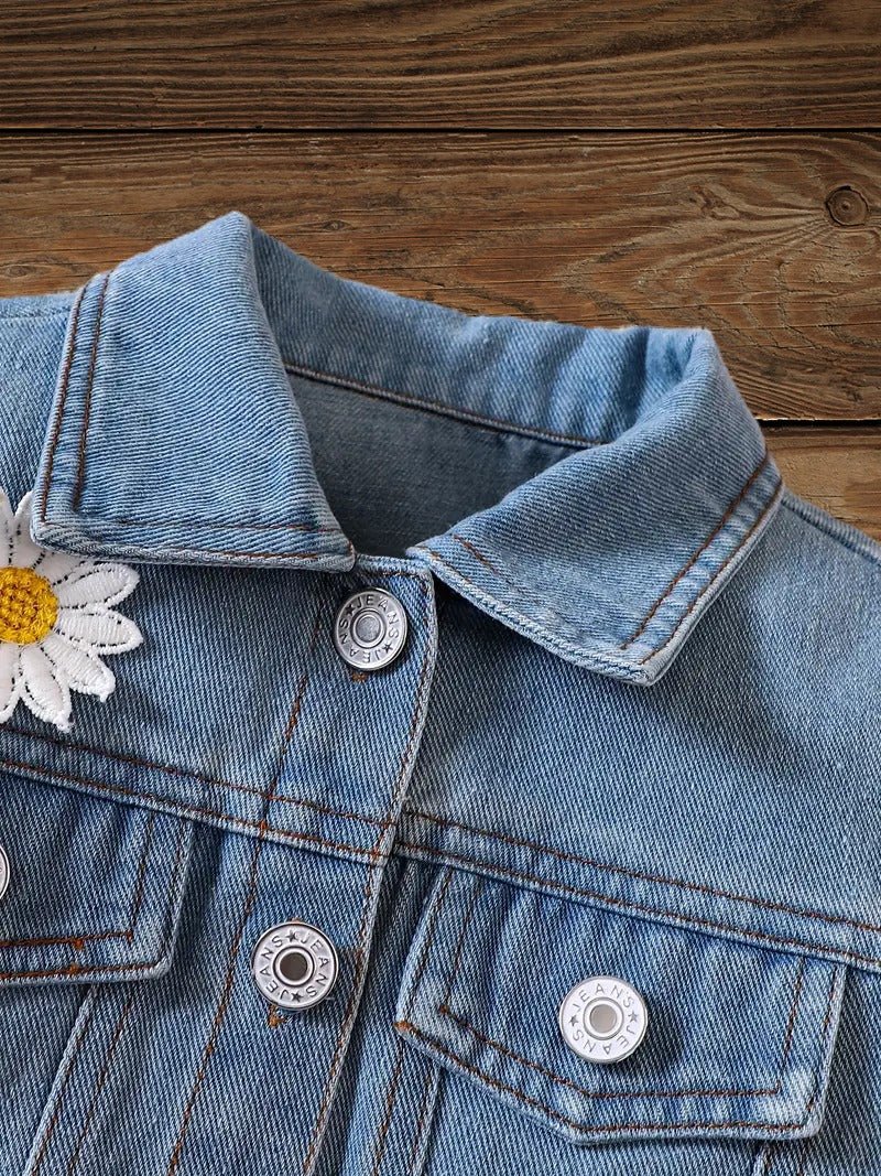 Collar and front pocket detail of toddler denim jacket with daisy patch accent.