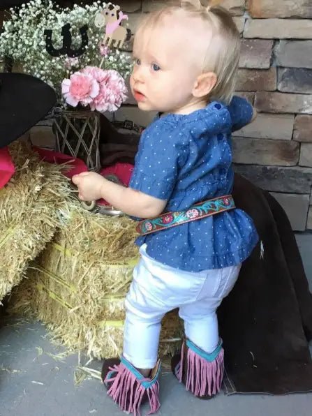 Side view of baby walking in pink fringe boots