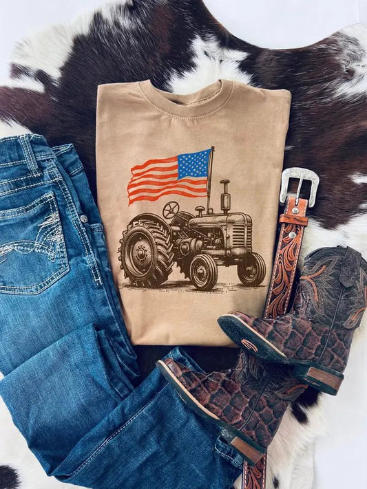 Vintage tractor kids t-shirt with American flag styled with jeans, belt, and cowboy boots on cowhide background.