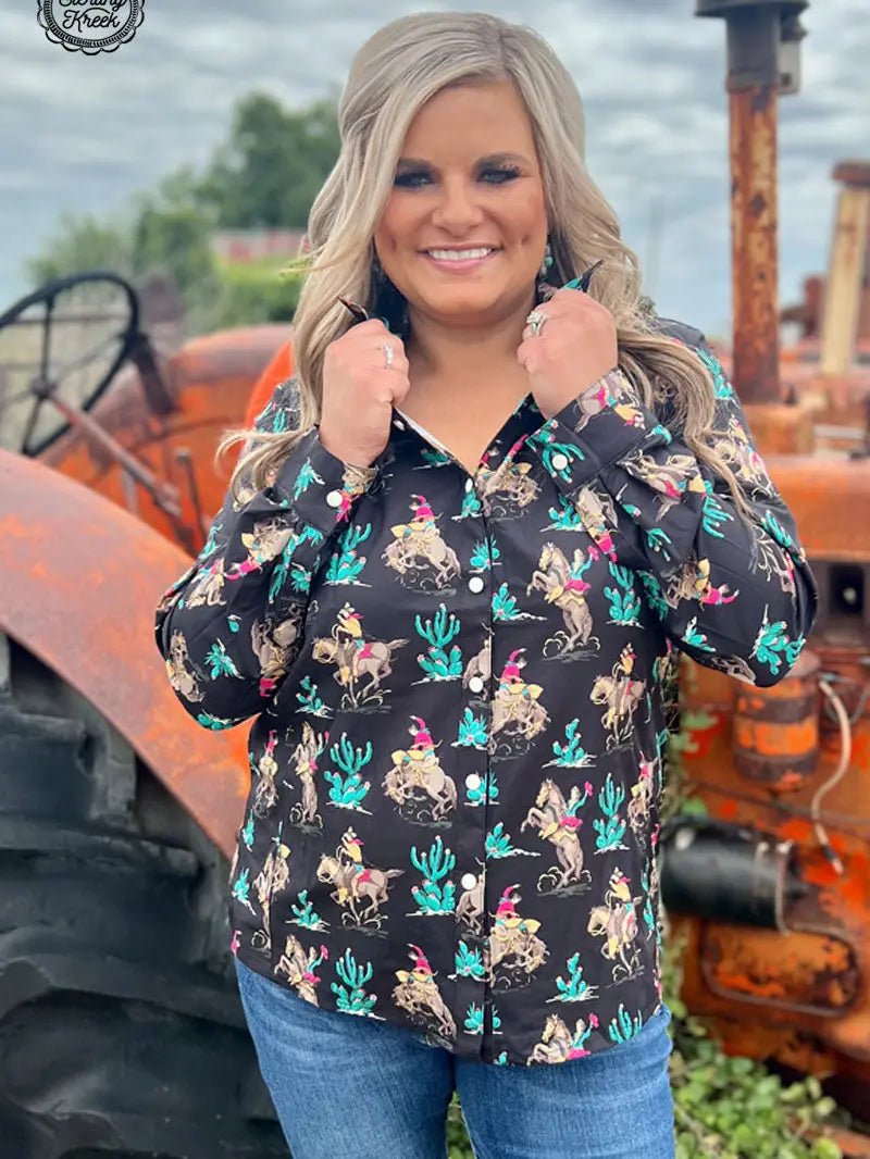 Smiling woman modeling western grit black rodeo shirt, hands up at collar.