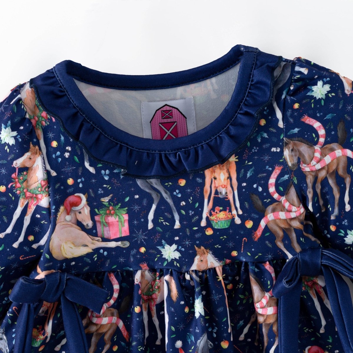 Ruffled navy neckline and festive horse print on the Christmas baby top.