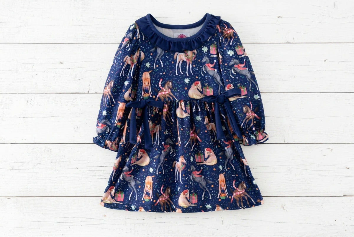 Front of a navy Christmas horse print dress with long sleeves, a ruffled neckline and two navy waist bows.
