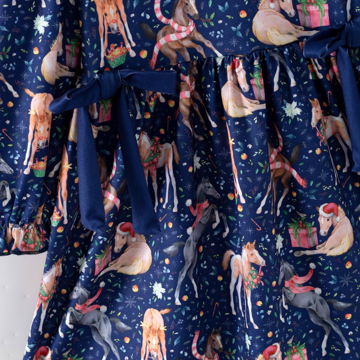Close-up of the gathered waist and navy bows on the Christmas horse dress.