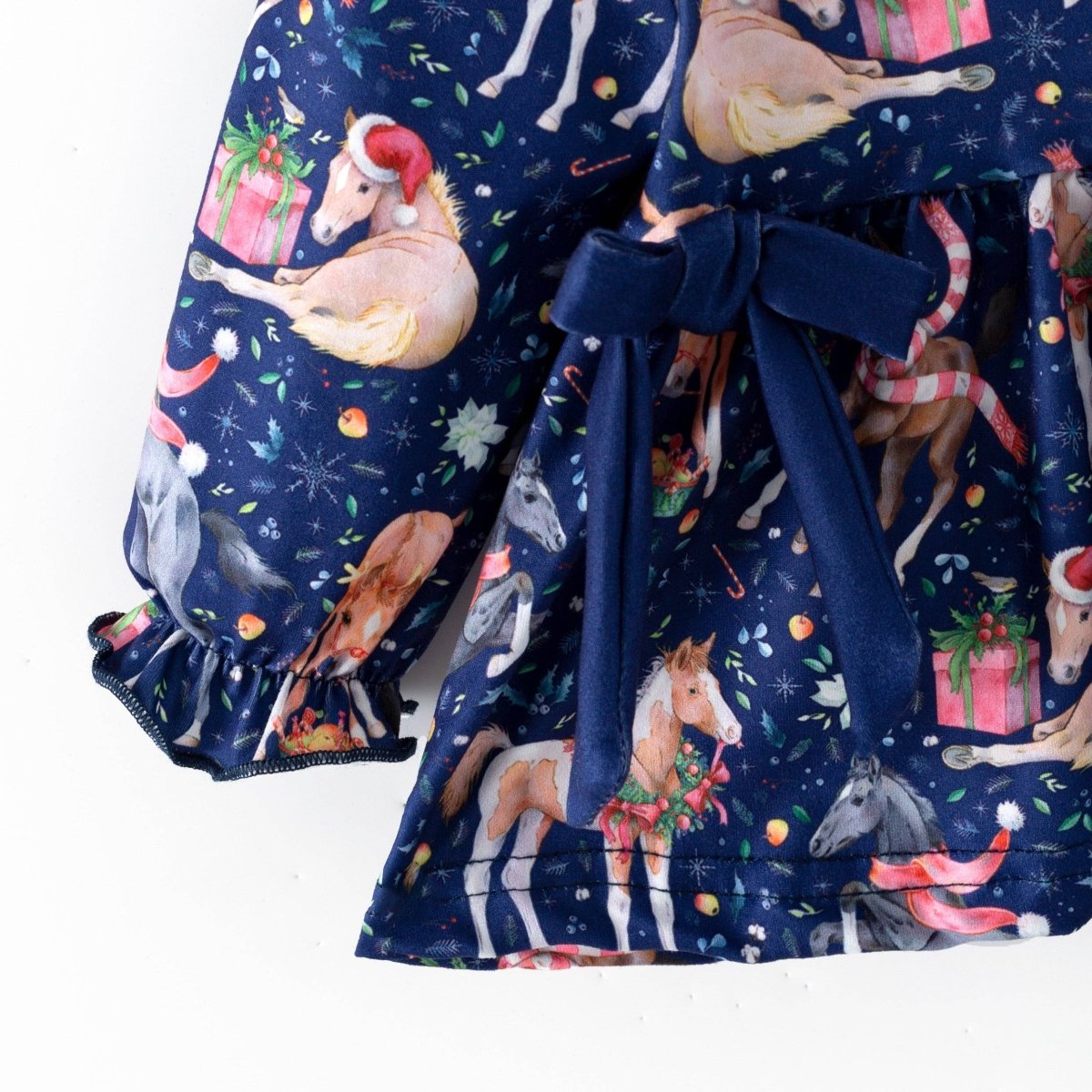 Navy waist bow, Christmas horse print and gathered sleeve cuff on the baby outfit top.