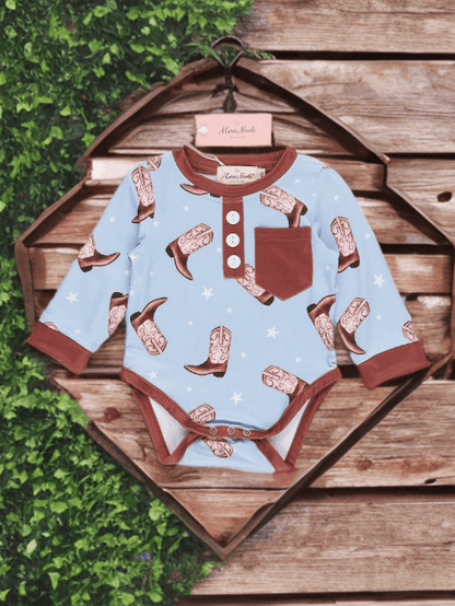 Baby onesie with cowboy boot pattern on a wooden background