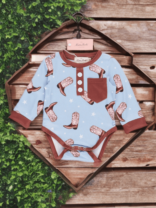 Baby onesie with cowboy boot pattern on a wooden background