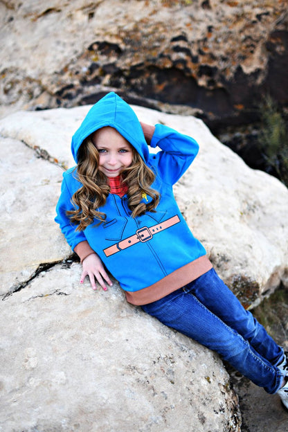 Child wearing a blue hooded jacket with a belt, sitting on rocks.