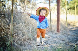 Child in cowboy hat and boots standing in a natural setting