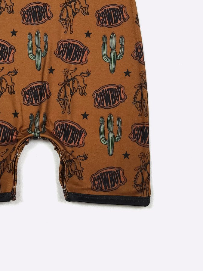 Close-up of a brown baby romper with a cowboy-themed pattern on a white background