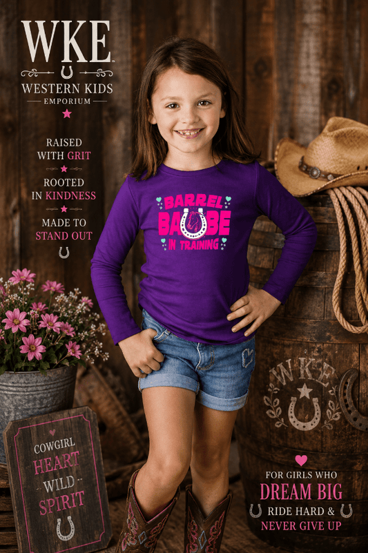 Young girl in a purple shirt with cowboy boots and a hat, standing against a wooden background with text about Western Kids Emporium.