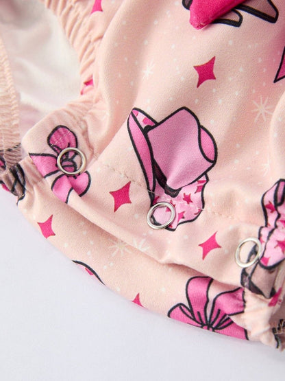 Close-up of pink fabric with bow and star patterns on a baby cowgirl romper  with light background