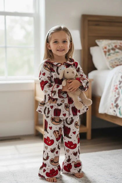 Young girl in a bedroom wearing heart-patterned pajamas holding a teddy bear.