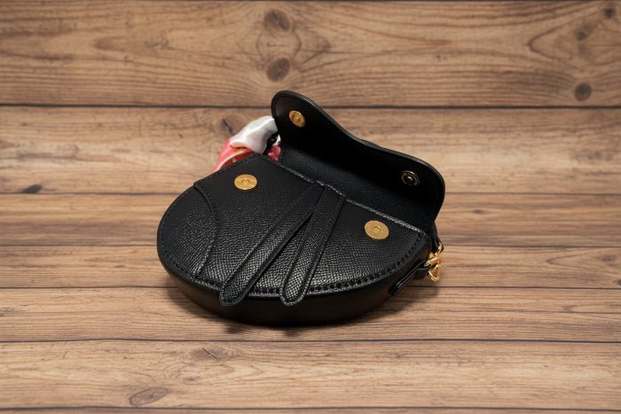 Black leather handbag with gold accents on a wooden background