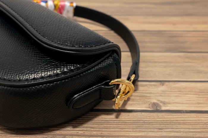 Black handbag with a gold clasp on a wooden background