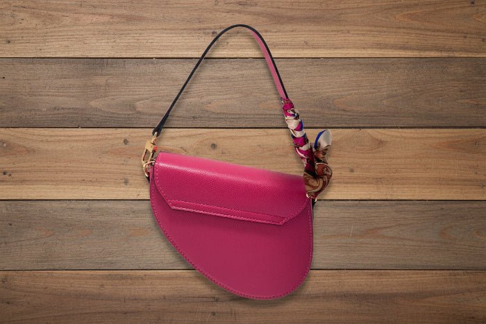 Pink handbag with a decorative scarf on a wooden background