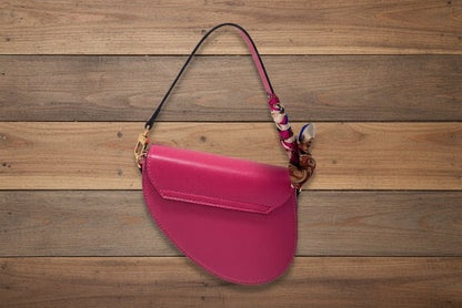 Pink handbag with a decorative scarf on a wooden background