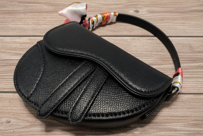 Black textured handbag with floral scarf on a wooden background