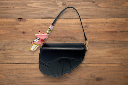 Black handbag with a colorful strap on a barn background